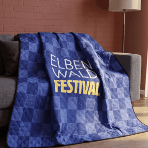Picknickdecke faltbar - Elbenwald Festival Blaue Decke mit dem Aufdruck "ELBEN WALD FESTIVAL" auf einem Sofa, ideal für Fans des Festivals, das Musik und Nerdkultur kombiniert. Perfekt für gemütliche Abende beim Zocken oder Filme schauen.