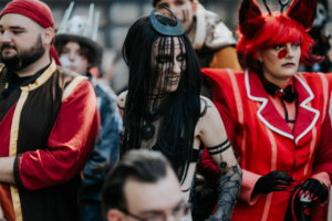 Menschen in kreativen Kostümen auf dem Elbenwald Festival, darunter eine Figur mit langen schwarzen Haaren und einem auffälligen Kopfschmuck, umgeben von weiteren verkleideten Teilnehmern, die die lebendige Atmosphäre des Events widerspiegeln.