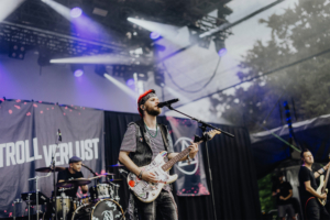 Kontrollverlust Live-Performance der Band "Kontrollverlust" auf dem Elbenwald Festival, das Musik und Nerd-Kultur verbindet. Der Frontmann spielt eine bunt gestaltete Gitarre, während das Publikum die energiegeladene Atmosphäre genießt.