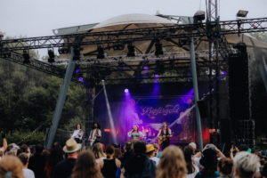 Kupfergold Auf der Bühne des Elbenwald Festivals spielt die Band Kupfergold vor begeistertem Publikum. Bunte Lichter und eine lebhafte Atmosphäre schaffen ein unvergessliches Erlebnis für Fans von Musik und Nerd-Kultur.