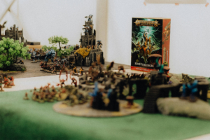 Detailreiche Miniaturenszenen von Warhammer Age of Sigmar auf dem Elbenwald Festival, mit verschiedenen Figuren und Landschaften, die das kreative und strategische Spielumfeld darstellen. Im Hintergrund ist das Einführungsset gut sichtbar.