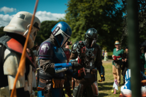 Olympiade Die Roten Adler vs. 501st Legion Drei Cosplayer in beeindruckenden Rüstungen stehen auf dem Elbenwald Festival, umgeben von einer begeisterten Menge. Die Charaktere zeigen eine Mischung aus Sci-Fi-Elementen und Fantasie, während sie sich auf ein Event vorbereiten.