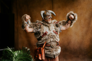 Cosplay Catwalk Ein kostümierter Teilnehmer des Elbenwald Festivals zeigt stolz seine detailreiche, felle Besetzung mit Hörnerhelm und Ledergürtel. Der Ausdruck von Begeisterung und Engagement spiegelt die kreative Atmosphäre des Festivals wider.