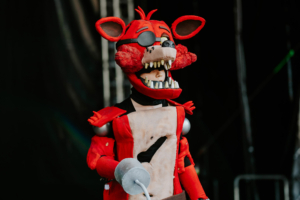 Cosplay Contest Ein Cosplay von Foxy aus Five Nights at Freddy's auf dem Elbenwald Festival, das eine bunte und kreative Atmosphäre zeigt. Der Charakter trägt ein detailliertes Kostüm mit markanten Merkmalen und steht vor einer dunklen Bühnenkulisse.