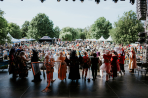 Cosplay Contest Blick von der Bühne auf das Publikum beim Elbenwald Festival, das eine lebhafte Mischung aus Musik und Kostümen zeigt. Im Vordergrund stehen verkleidete Teilnehmer, während im Hintergrund eine große Menge in festlicher Atmosphäre feiert.