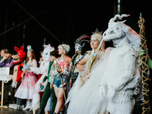 Cosplay Contest Bunt kostümierte Teilnehmer stehen auf der Bühne des Elbenwald Festivals, das Musik und Nerd-Kultur vereint. Die Gruppe zeigt kreative und fantasievolle Outfits, die von verschiedenen Charakteren inspiriert sind, und zieht die Aufmerksamkeit der Zuschauer auf sich.
