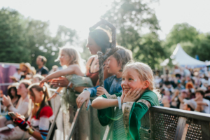 Cosplay Contest Glückliche Kinder in Kostümen genießen die Atmosphäre des Elbenwald Festivals. Die Zuschauer stehen am Bühnenrand, während die Sonne scheint und eine lebendige Festivalatmosphäre entsteht. Ein unvergessliches Erlebnis für Fans von Musik und Fantasy.