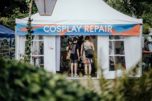 Cosplay Repair Zelt für Cosplay-Reparaturen auf dem Elbenwald Festival, mit Besucher:innen, die auf dem Weg zur Reparaturstation sind. Bunte Dekoration und einladendes Ambiente unterstreichen die kreative Atmosphäre des Festivals.