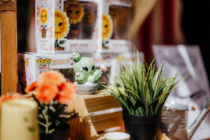 Funko Flora Pops Bunte Dekoration mit einem niedlichen Kaktus-Figur, künstlichen Blumen und Pflanzen, umgeben von Funko Pop! Figuren auf dem Elbenwald Festival, das eine Mischung aus Musik und Nerd-Kultur bietet. Perfekt für Sammler und Fans.