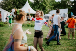 Historische Tänze Fröhliche Festivalbesucher tanzen auf dem Elbenwald Festival, umgeben von bunten Kostümen und Zelten. Die Atmosphäre ist lebhaft und einladend, während die Teilnehmer ihre Liebe zu Musik und Nerd-Kultur feiern.